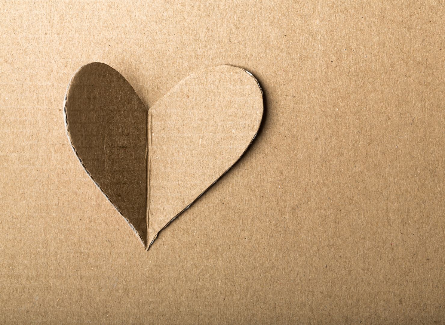 Hintergrund aus Karton auf dem ein Stück Karton in Herzform liegt